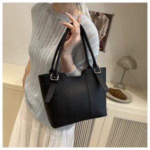 Detail view of black lychee grain leather tote bag with elegant gold hardware buckles