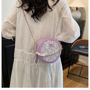 Detail of round purple geometric bag featuring elegant pearl chain and gold hardware