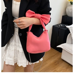 Détail du grand nœud rose et de la chaîne argentée sur un sac à main en daim