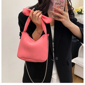 Gros plan d'un sac à main rose avec poignée en nœud et bandoulière en chaîne fine
