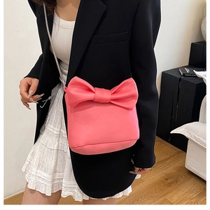 Gros plan sur le sac seau en forme de nœud rose avec bandoulière chaîne sur un mannequin