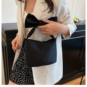 Détail du sac à main noir à nœud avec chaîne en métal porté par un mannequin chic