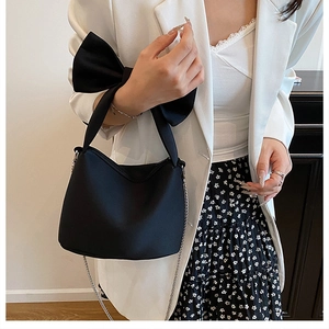 Détail du grand nœud noir et de la chaîne argentée sur ce sac à bandoulière élégant