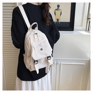 Détail d'un mini sac à dos blanc cassé multifonctionnel porté par un mannequin
