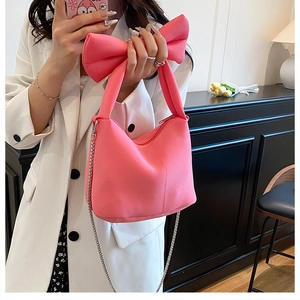 Détail du sac à main rose avec gros nœud en tissu doux et bandoulière en chaîne métallique