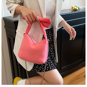 Vue détaillée du sac à main rose à nœud avec bandoulière chaîne argentée sur modèle