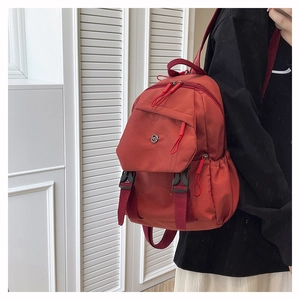 Detail shot of brick red nylon chest bag with functional pockets and secure buckles