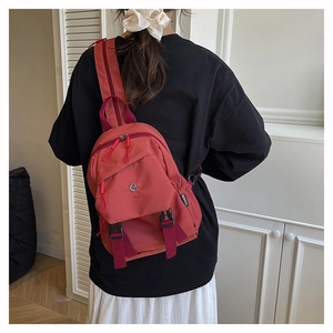 Rear view of a red nylon crossbody chest bag with adjustable strap and fashion label