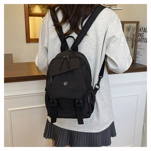 Détail du sac à dos en nylon noir avec sangle tendance et logo métallique sur modèle