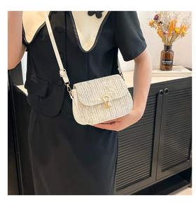 Close-up of woven saddle bag featuring a gold horseshoe clasp and lace flower accents