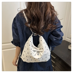 Gros plan d'un sac cabas matelassé blanc avec breloque cœur et nœud sur un modèle