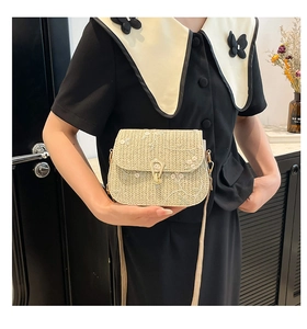 Detail of beige woven crossbody bag with pink floral embroidery and gold horseshoe lock