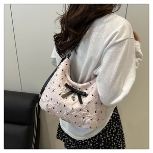 Détail du sac à bandoulière plissé rose clair avec nœuds noirs et pendentif cœur