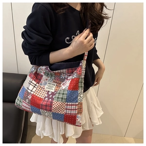 Detail of patchwork tote bag featuring floral and plaid patterns with fabric label