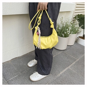 Detail of yellow pleated croissant bag featuring soft PU leather and decorative tassel