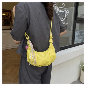 Chic yellow crescent shoulder bag featuring a decorative knot strap and heart charm detail