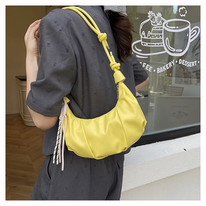 Detail view of bright yellow pleated cloud bag with stylish canvas knot decoration