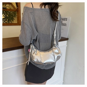 Silver crescent shoulder bag featuring side pleats and a pink heart pendant charm