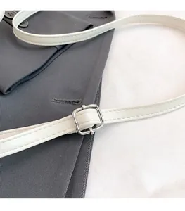 Detail of white leather shoulder strap featuring silver buckle and fine edge stitching
