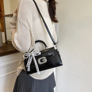 Black glossy pleated mini crossbody bag with a metal G logo and large pearl lace bow charm