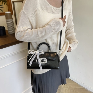 Elegant black leather handbag with silver G logo and pearl lace bow detail on shoulder strap