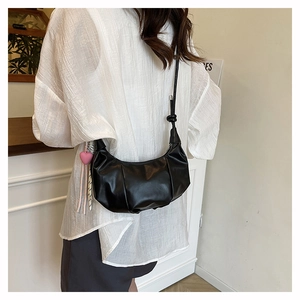 Detailed side view of a black crescent crossbody bag with decorative heart pendant and knot