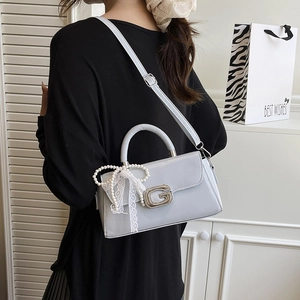 Detail of light blue-gray square crossbody bag with G buckle and pearl lace charm