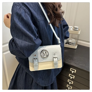 Blue and beige patchwork crossbody bag with silver M logo worn by a model