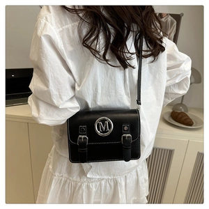 Détail d'un sac bandoulière noir avec logo M argenté et sangles métalliques au design chic