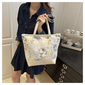 Dettaglio della borsa tote in tweed floreale con frange e base in pelle crema