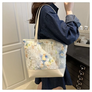 Dettaglio del ricamo floreale e base in pelle color crema su borsa tote da donna