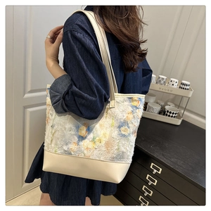 Dettaglio di ricamo floreale e cuciture in pelle crema sulla borsa tote da donna a spalla