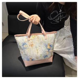 Dettaglio della borsa tote floreale bianca con manici in pelle rosa e tessuto testurizzato