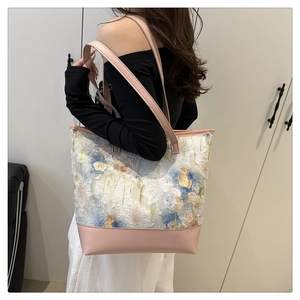 Dettaglio della borsa tote in tela ricamata con manici in pelle rosa e nappe morbide