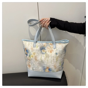 Dettaglio borsa tote azzurra con ricamo floreale 3D e rifiniture in tessuto di pizzo