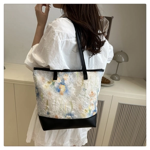 Dettaglio del ricamo floreale 3D bianco e delle finiture in pelle nera della borsa