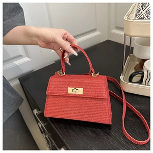 Detail of red glitter trapezoid handbag featuring gold rectangular twist-lock clasp