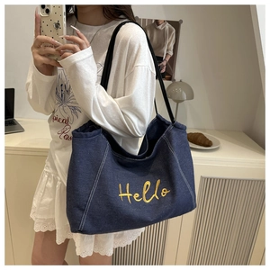 Detail of blue denim tote bag with yellow Hello embroidery and contrast white stitching