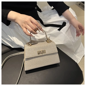 Detail of champagne gold glitter handbag with metallic clasp and structured top handle