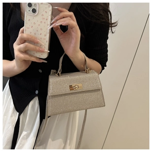 Detailed close-up of champagne gold glitter handbag with metallic turn-lock and top handle