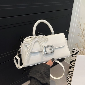Détail du sac blanc avec boucle G en diamant, pendentif nœud perlé et bordure en dentelle