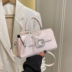 Detail of light pink patent leather bag featuring a crystal G buckle and pearl lace bow