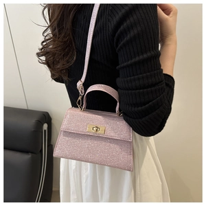 Detailed macro view of pink glitter texture and gold twist lock on mini crossbody handbag