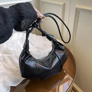 Elegant black faux leather crescent shoulder bag with pleated details and knot strap