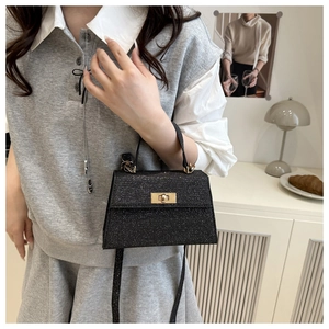 Detail of glitter black handbag with gold turn-lock and detachable shoulder strap