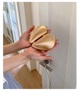 Close-up of gold heart shell evening bag with radial rib design and metal chain strap