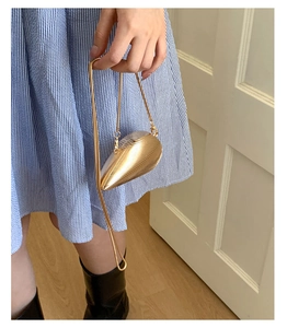 Macro view of golden shell-shaped evening clutch bag with refined metal ripple texture