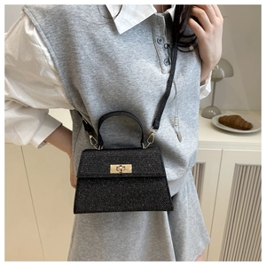 Detail of glittery black crossbody bag with golden twist lock and star-like texture