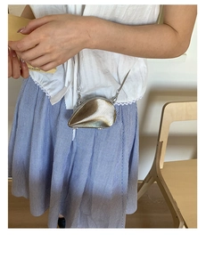 Detail of shell-shaped metallic crossbody bag with ribbed texture and elegant chain strap