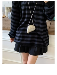Silver metallic seashell crossbody bag with chain strap on a model wearing striped top